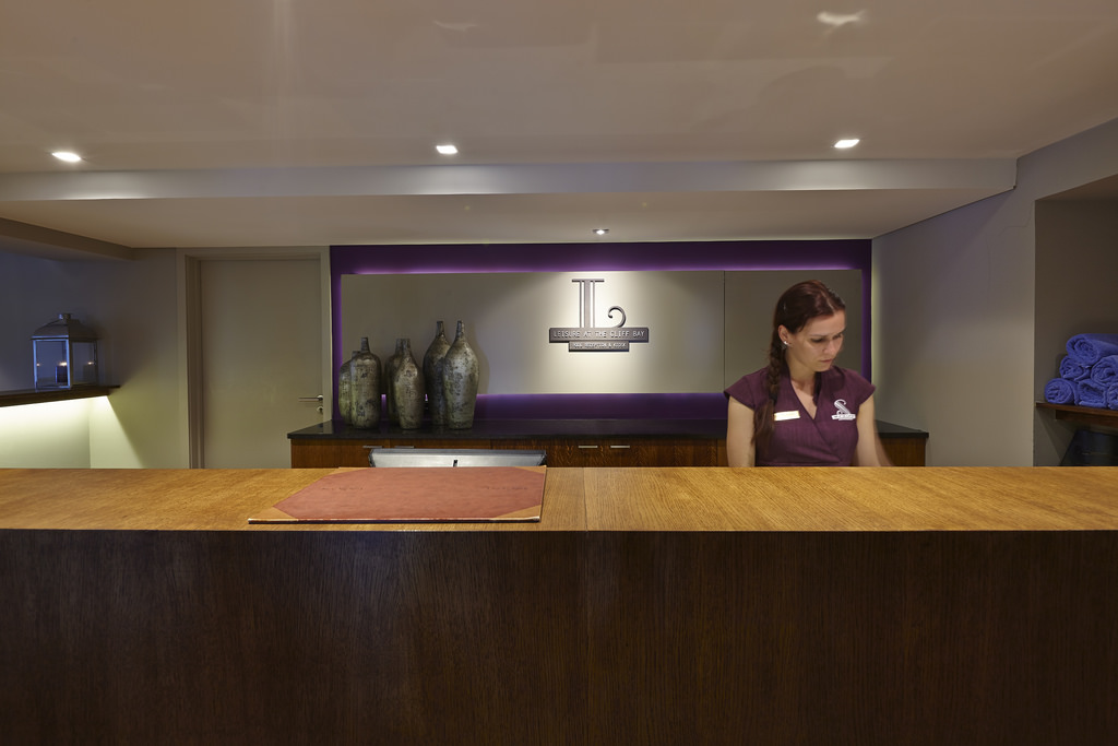 a female receptionist stands at a spa reception desk
